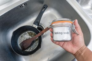 A Hand Holds a Container of Baking Soda