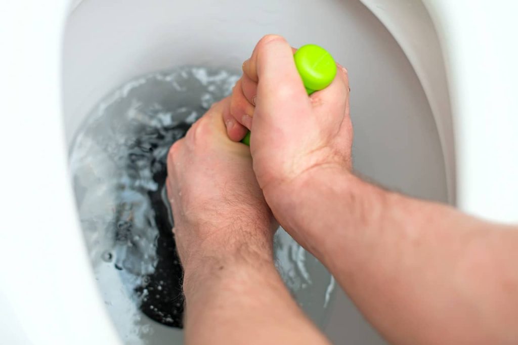 Plumber Trying to Unclog Toilet with Hand Plunger